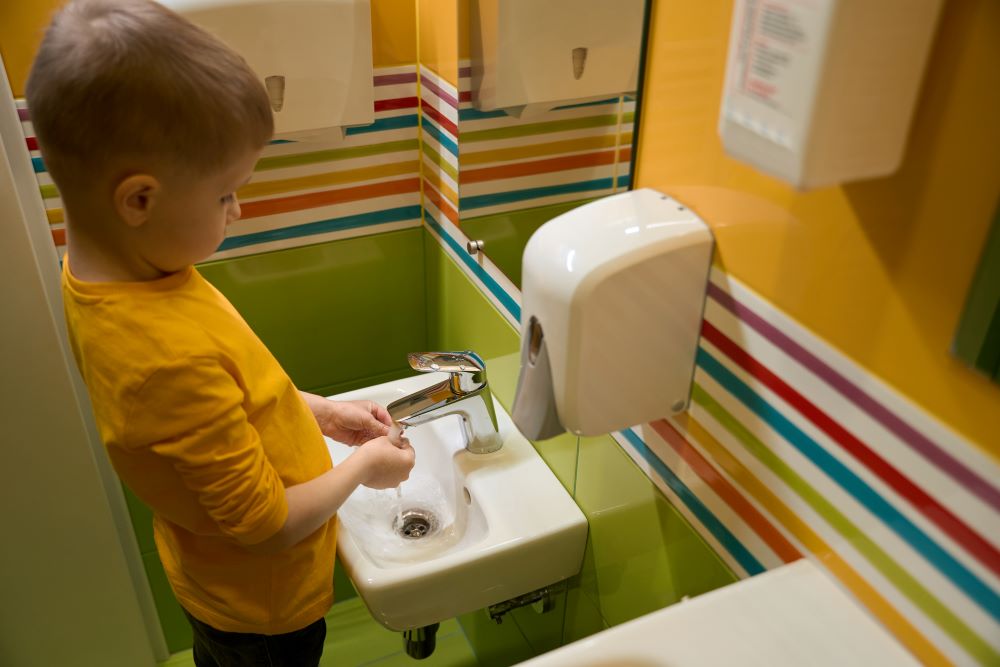 child is cleaning his hands in the washroom indoors