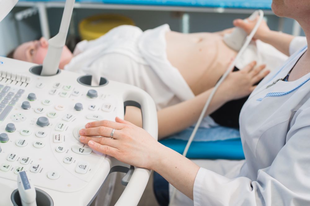 Close up of incognito doctor using ultrasound equipment for screening pregnant woman