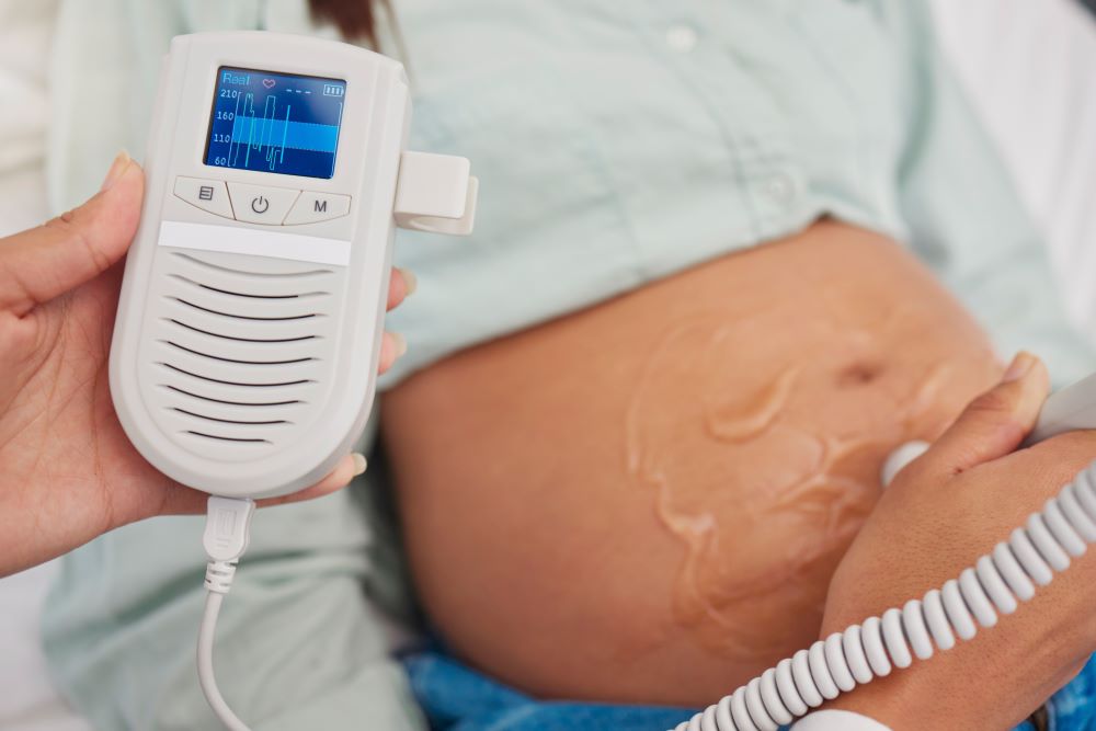 Pregnant woman with doctor hands and heart rate monitor for baby healthcare