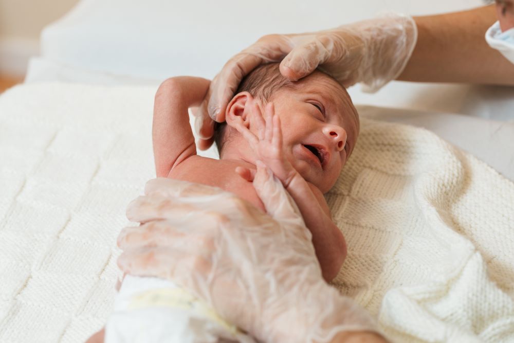 Professional physiotherapist performing a sternocleidomastoid evaluation in a newborn baby